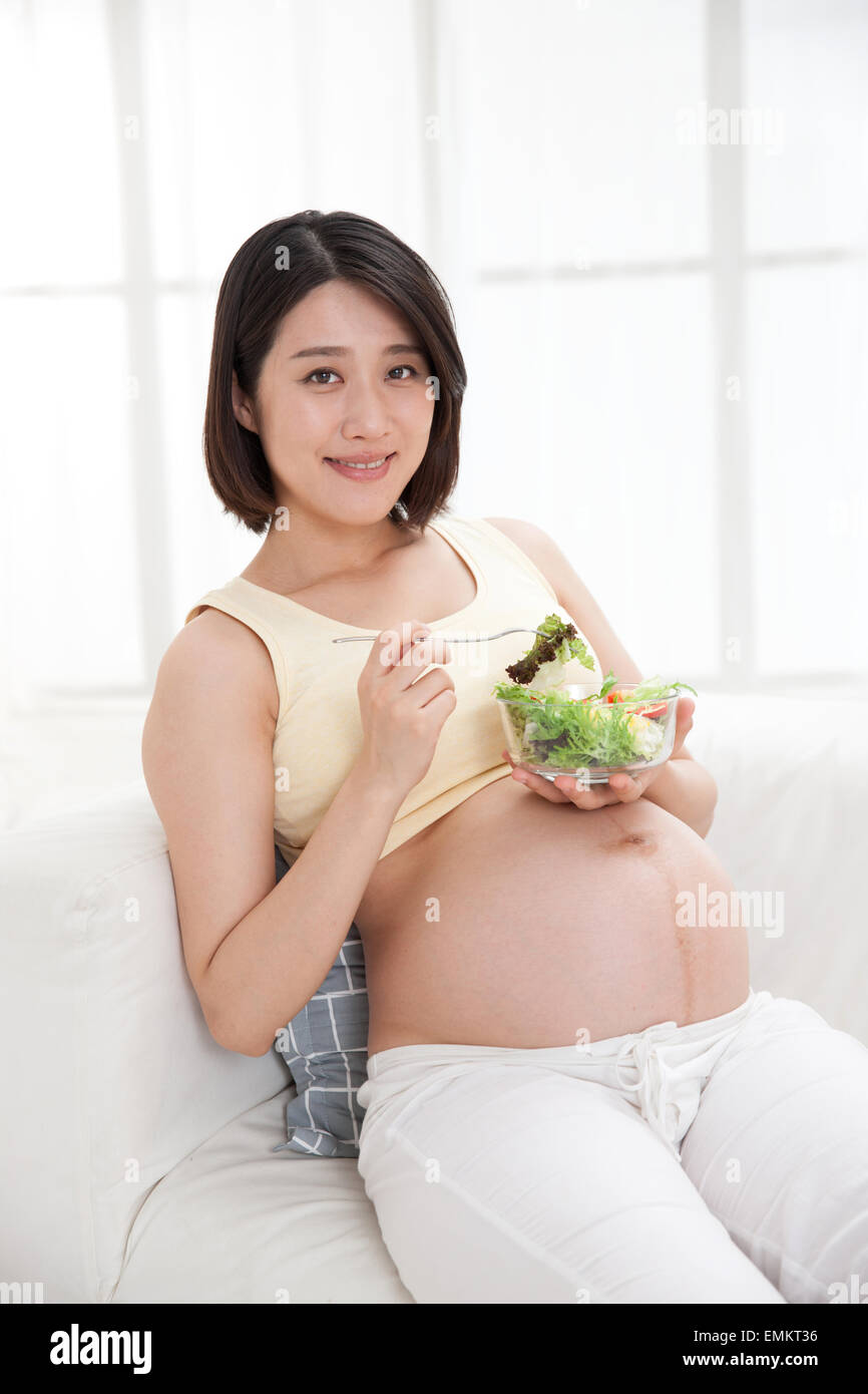 Pregnant women eat salad leaning on the sofa Stock Photo Alamy