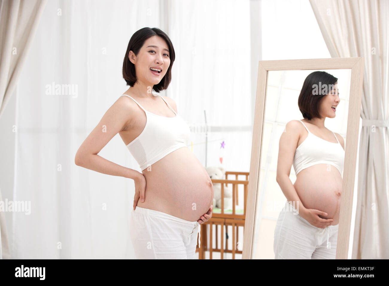 The pregnant woman standing in front of the mirror Stock Photo