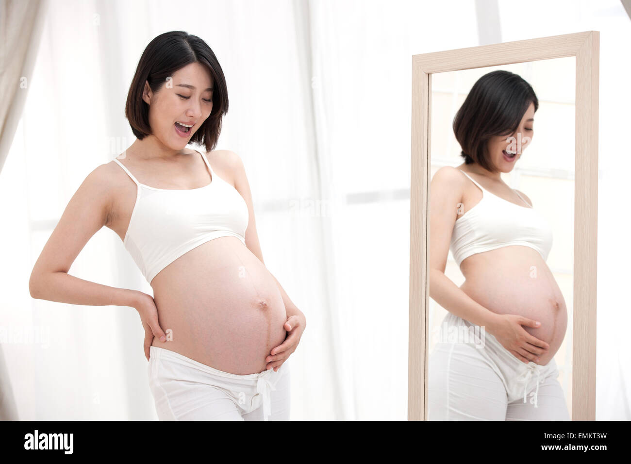 The pregnant woman standing in front of the mirror Stock Photo