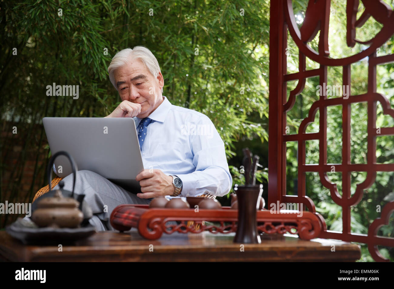Business older man sitting in the yard to use computer Stock Photo
