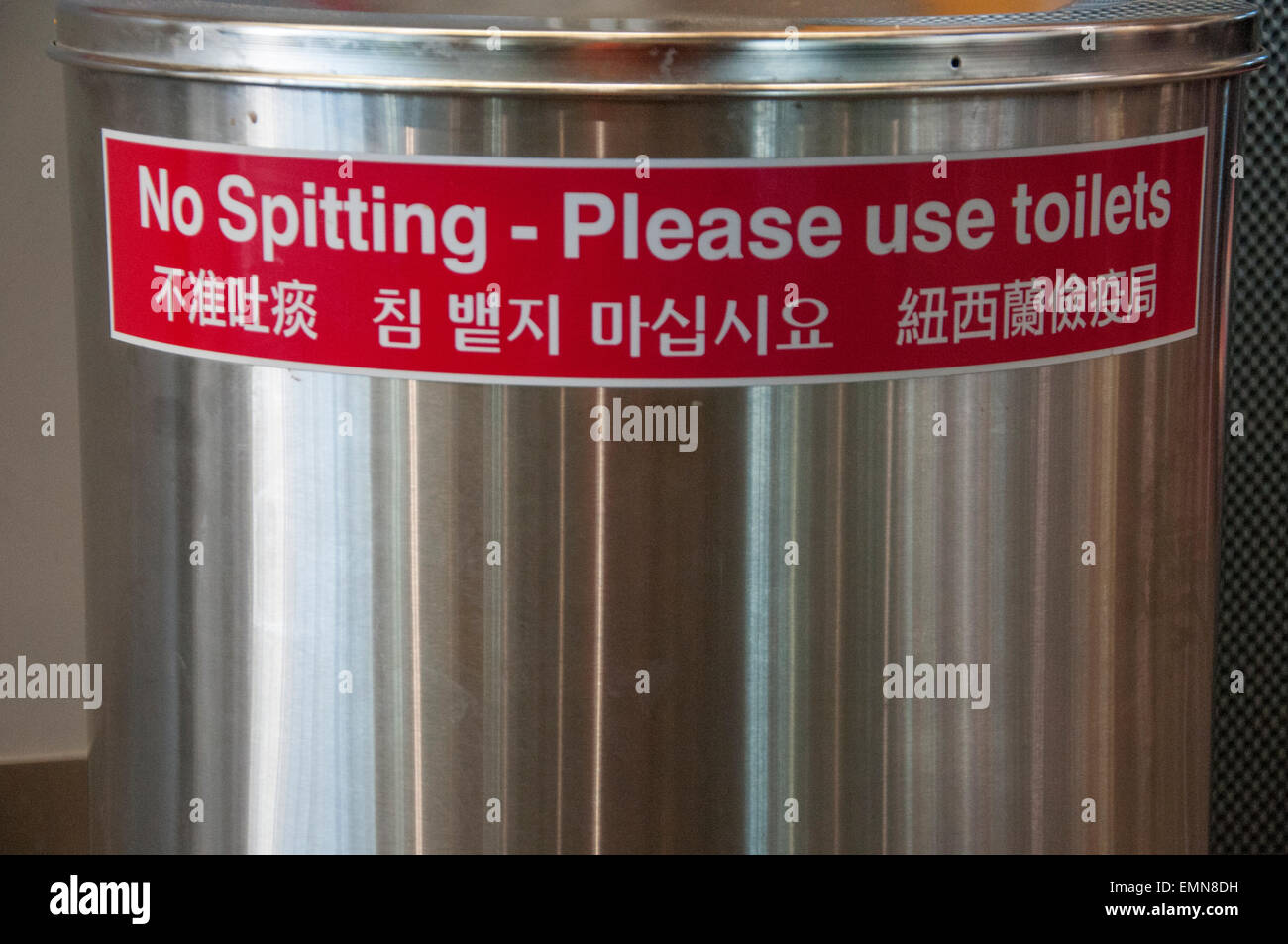 Multilingual No Spitting sticker at Auckland International Airport reveals cultural differences with Asian travellers Stock Photo