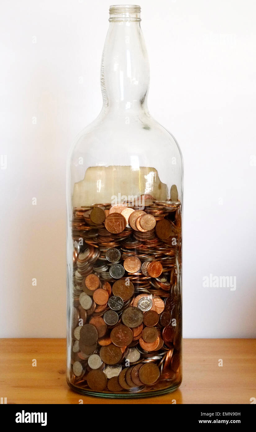 large glass bottle nearly full of loose change being saved Stock Photo