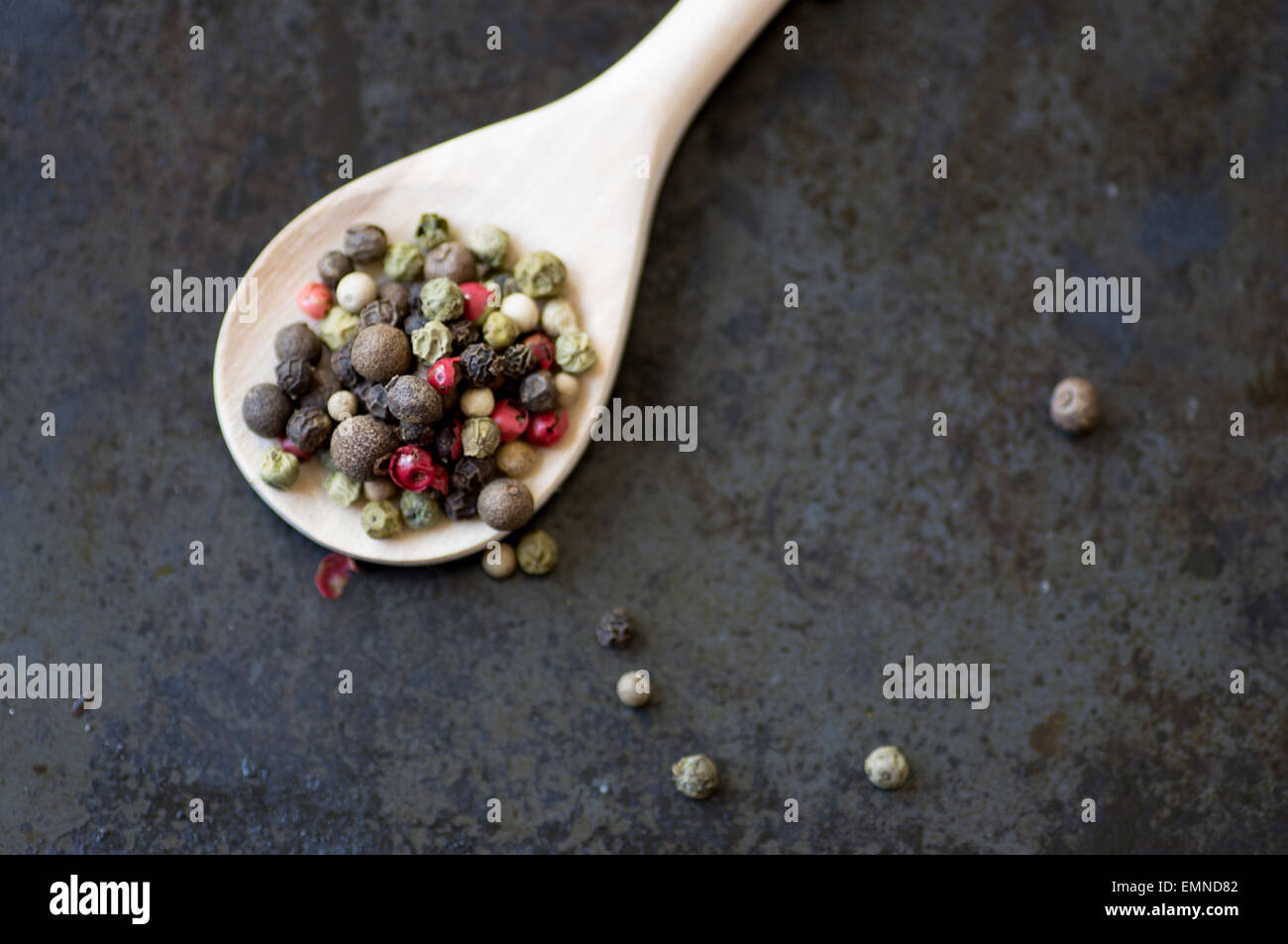 Mixture of different peppercorns in a wooden spoon top view Stock Photo