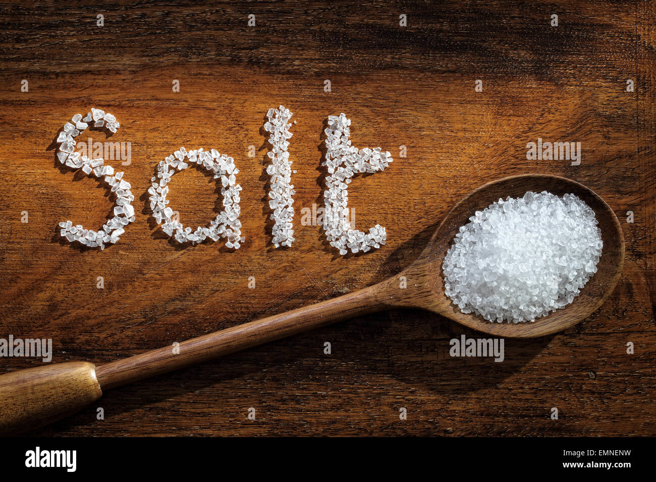 Sea salt on wooden spoon and the word salt written in grain Stock Photo