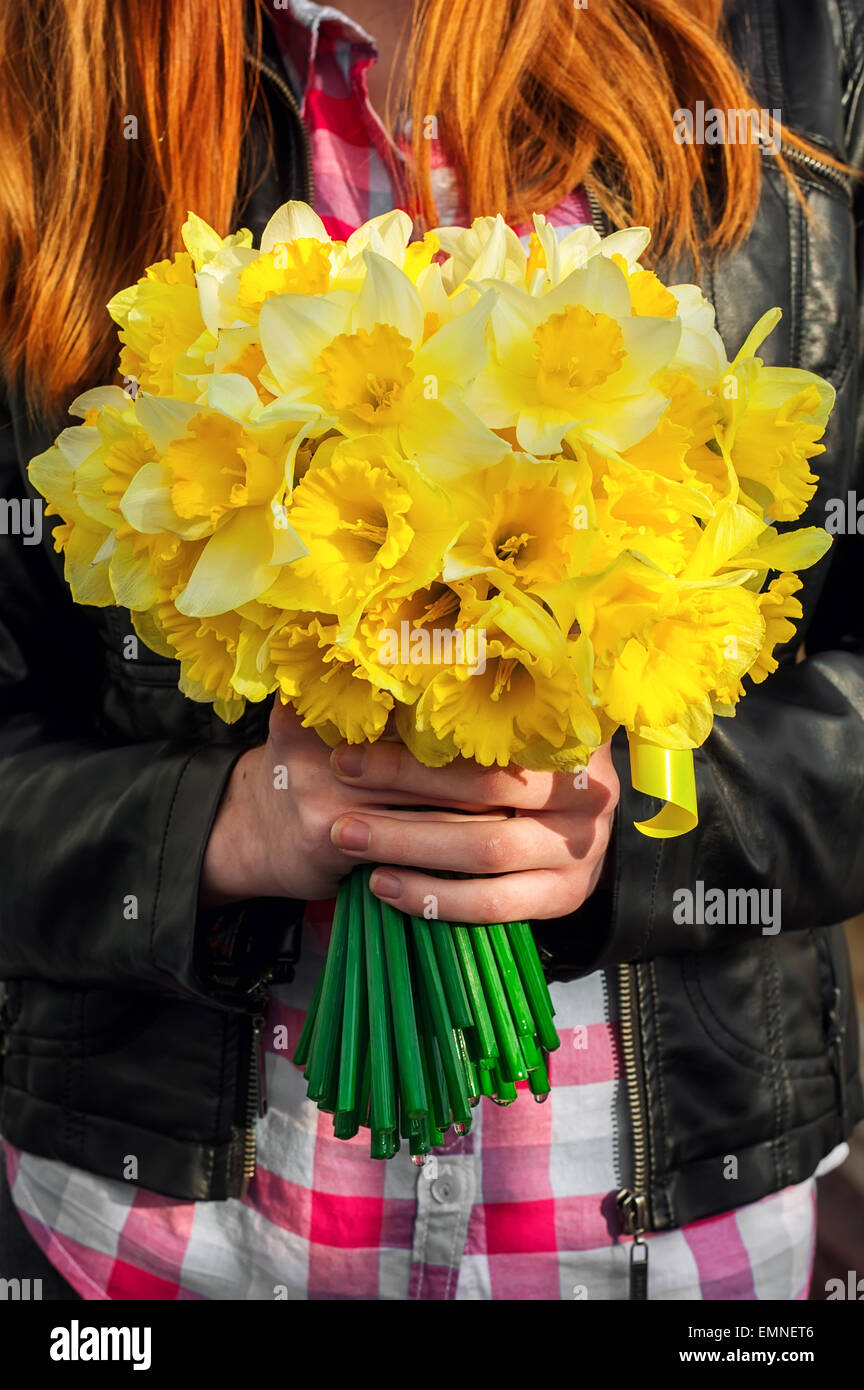 silhouette of girl with red hair with bouquet of daffodils hands.Selective focus Stock Photo