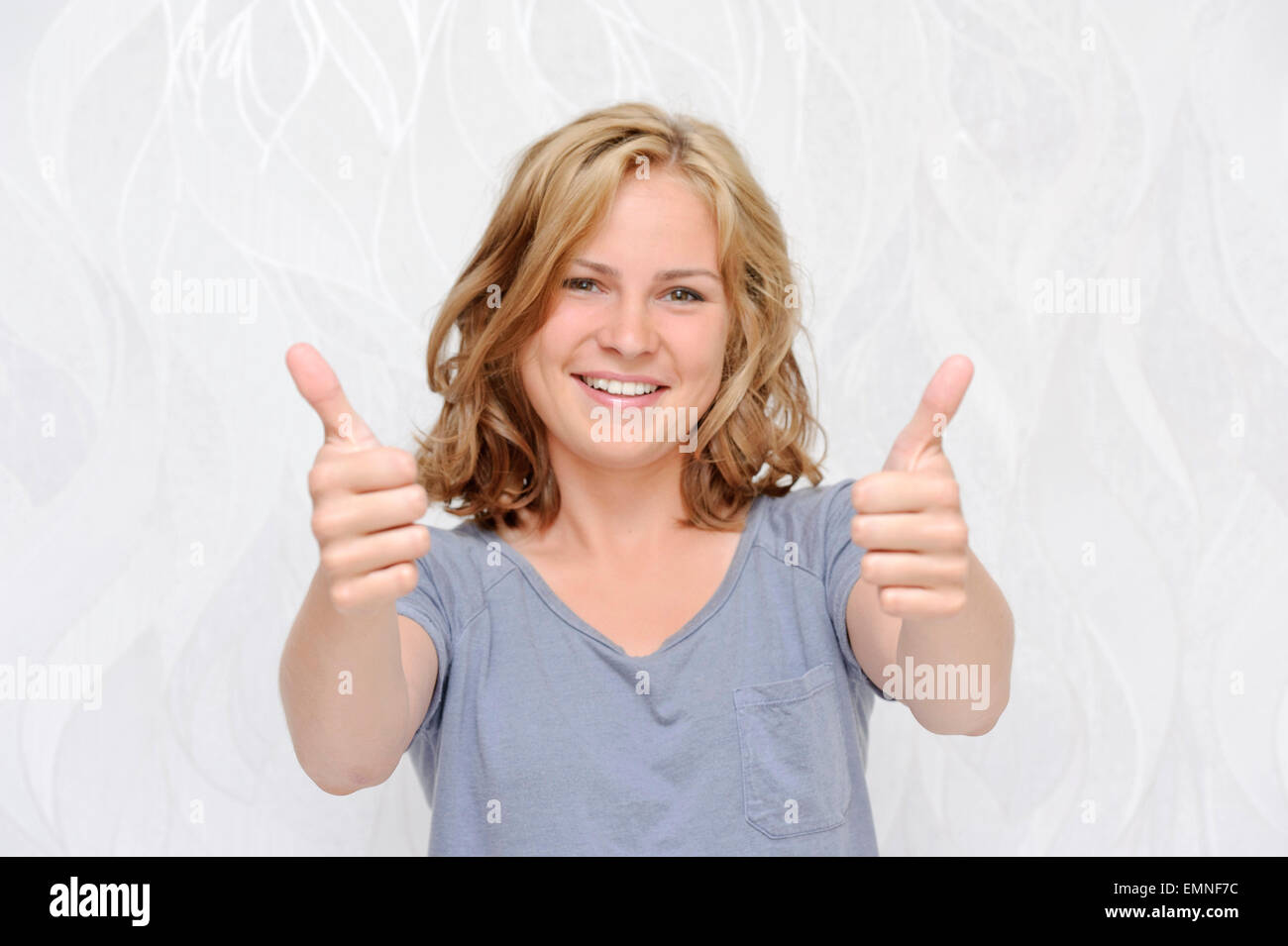 Young smiling woman showing thumbs up Stock Photo - Alamy
