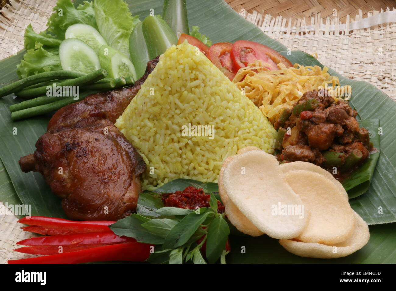 An Indonesian festive dish of yellow rice with meat and vegetables accompaniments. Stock Photo