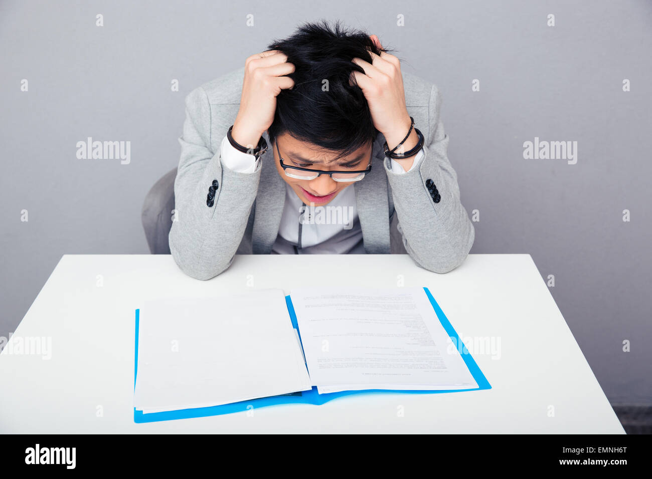 Worried businessman sitting at the table and reading papers in office Stock Photo