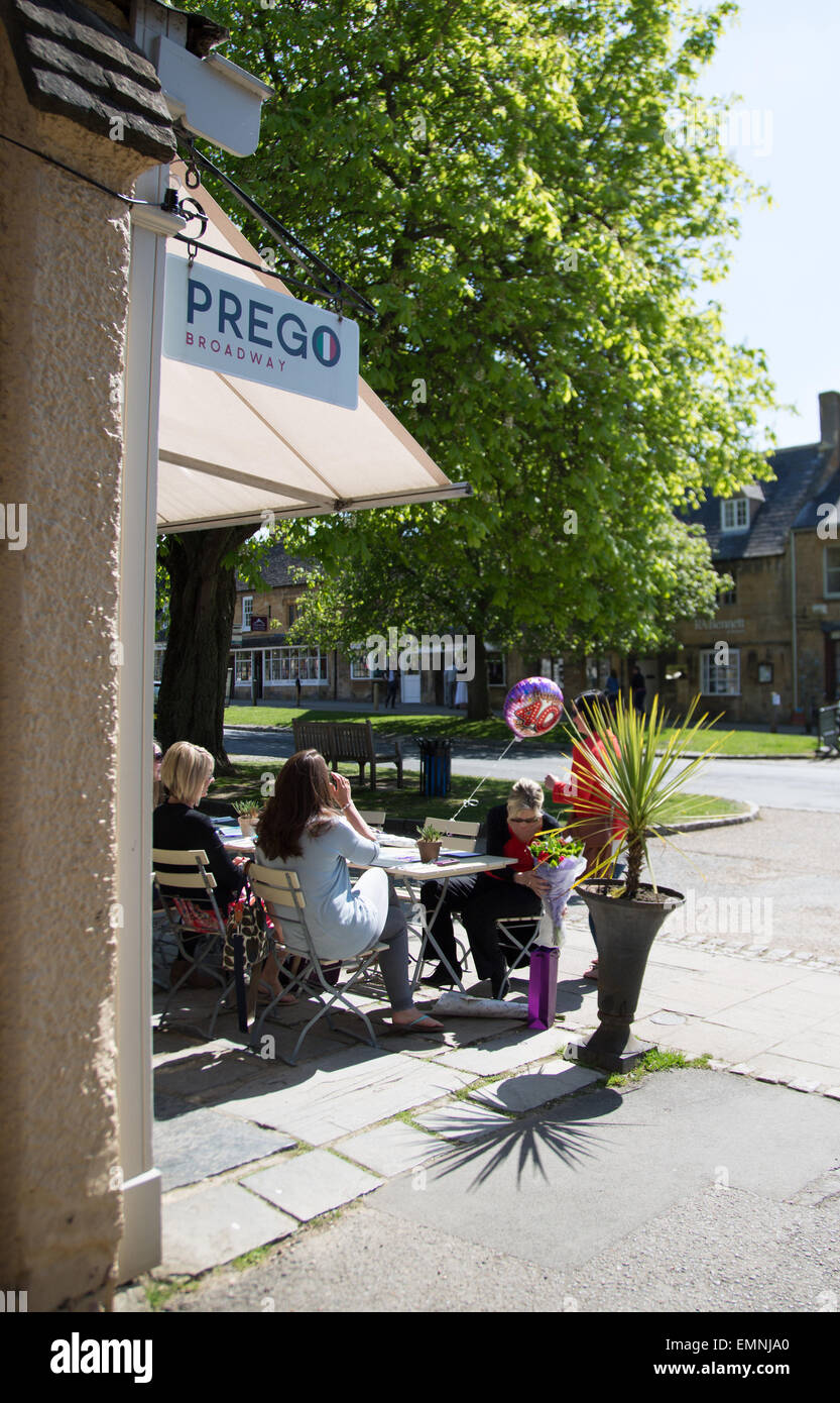 Women sat outside Prego restaurant in the cotswolds village of Broadway in the sunshine Stock Photo