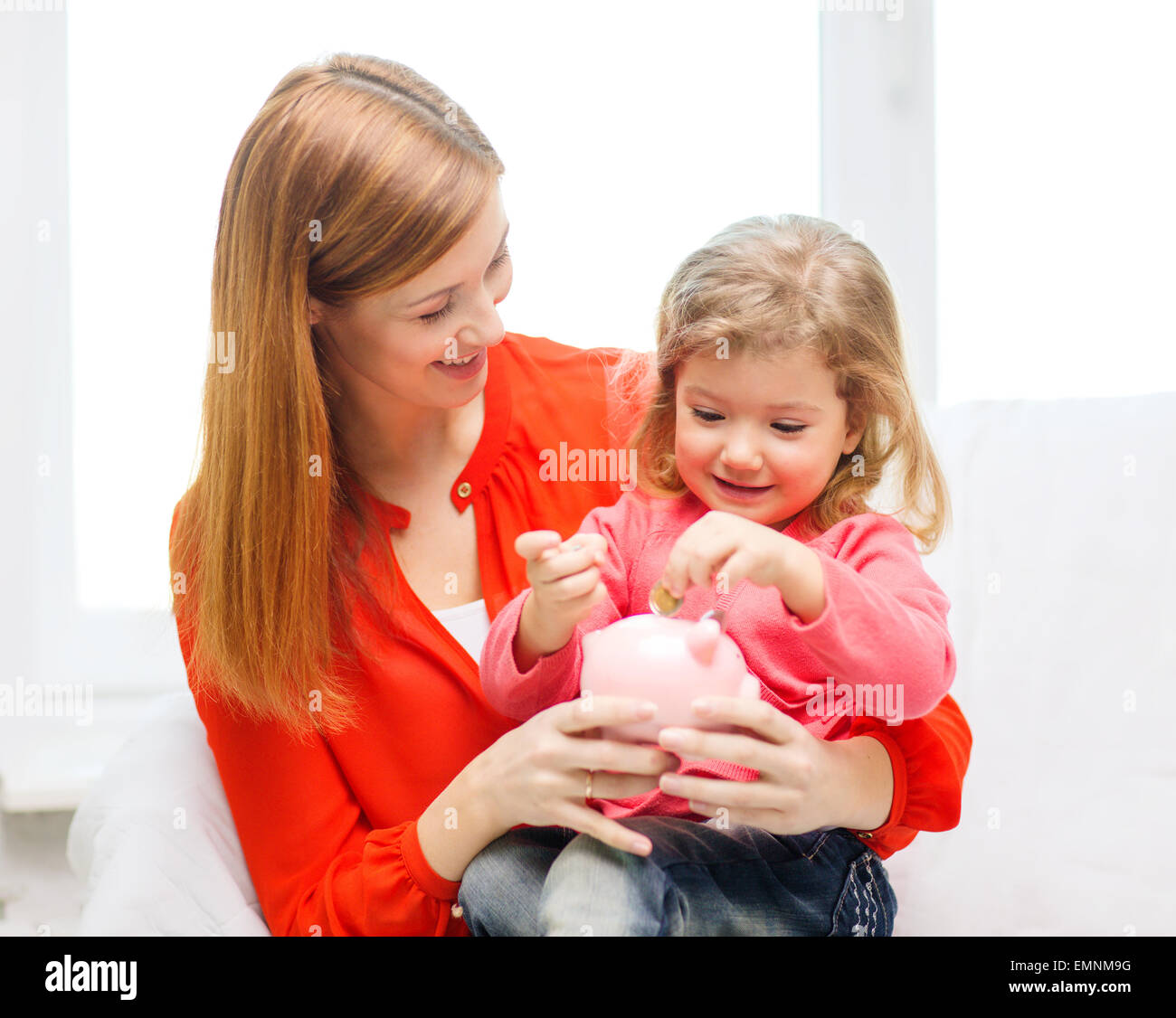 happy mother and daughter with small piggy bank Stock Photo - Alamy