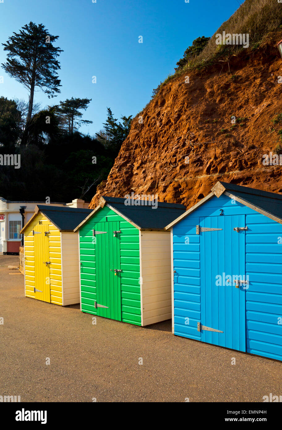 Brightly coloured painted wooden traditional beach huts on the promenade at Seaton a seaside resort in south Devon England UK Stock Photo