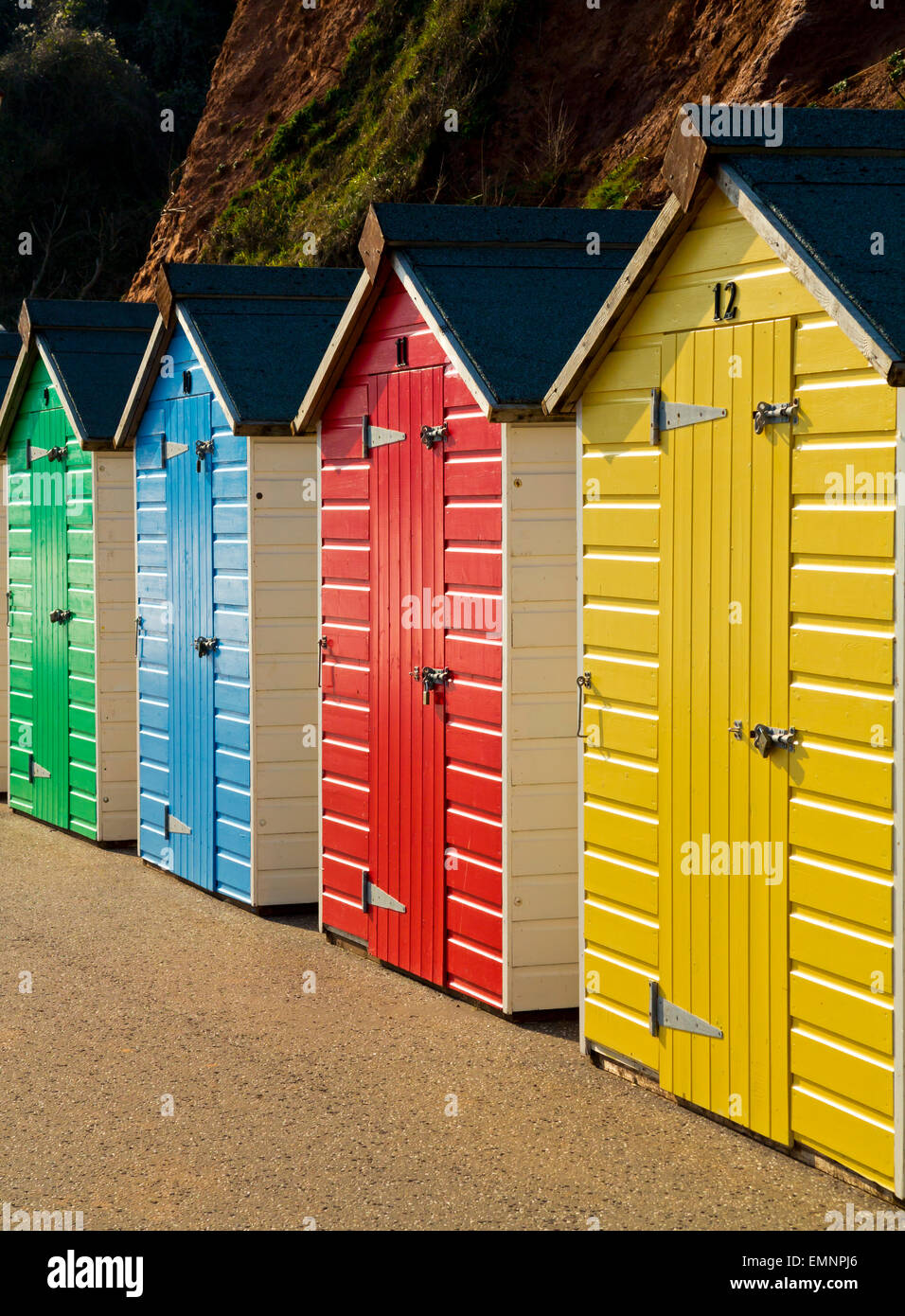 Brightly coloured painted wooden traditional beach huts on the promenade at Seaton a seaside resort in south Devon England UK Stock Photo