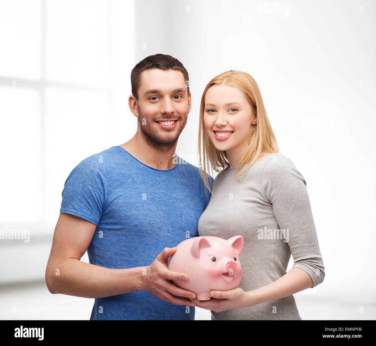 smiling couple holding big piggy bank Stock Photo - Alamy