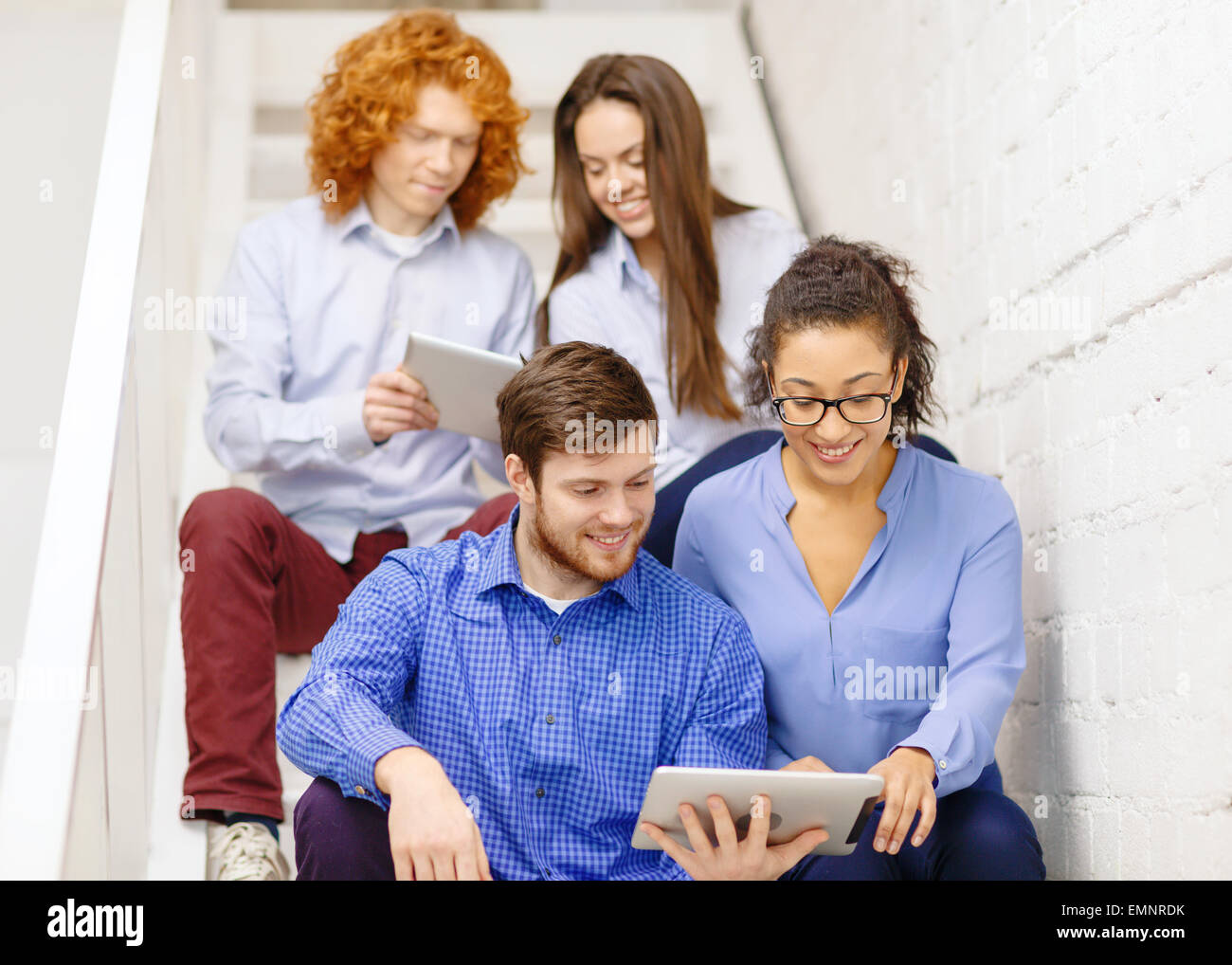 team with tablet pc computer sitting on staircase Stock Photo