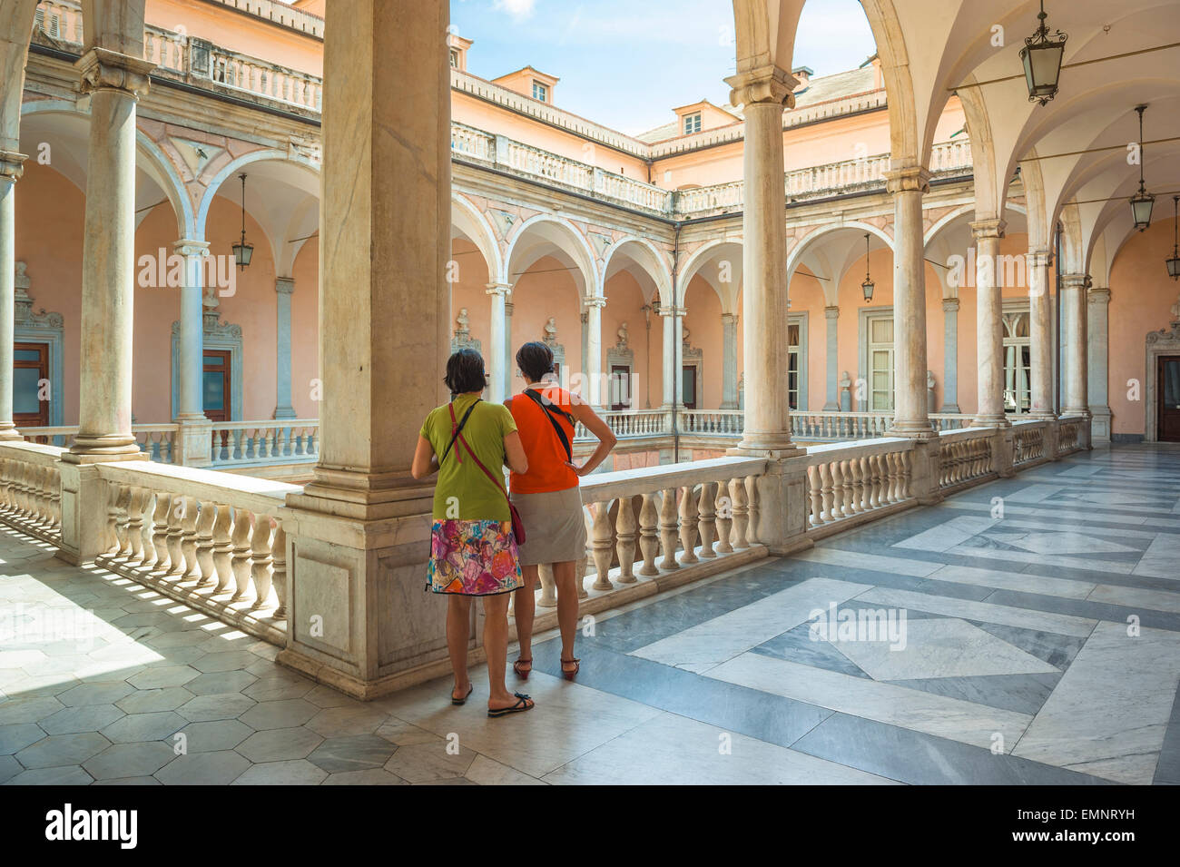 Mature women friends, rear view of two female friends in the Palazzo Tursi in Genoa looking down into the museum's courtyard, Genova, Liguria, Italy Stock Photo