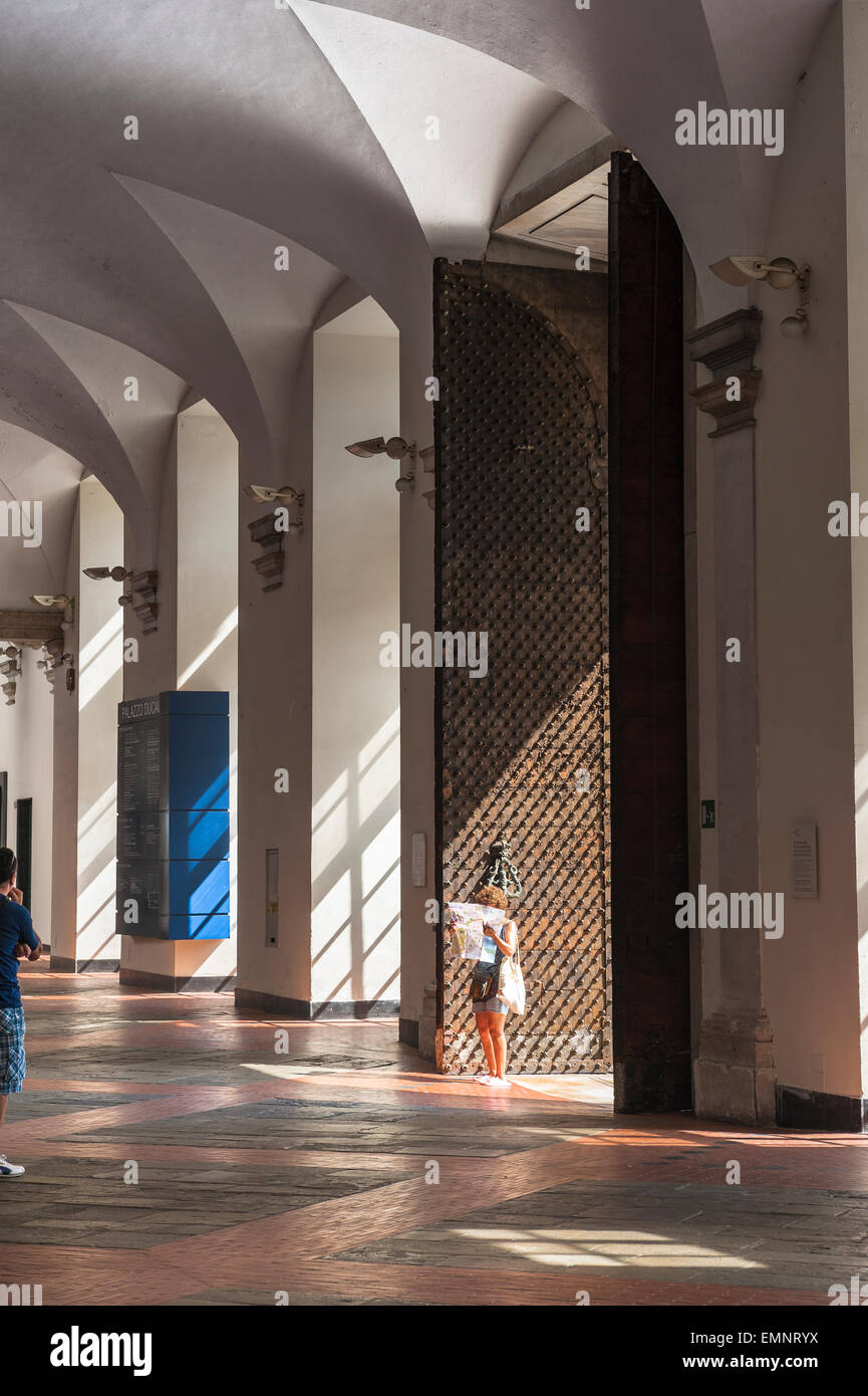 Woman travel, view of a solo woman traveler reading a map inside the vaulted atrium of the Palazzo Ducale, Genoa, Italy. Stock Photo