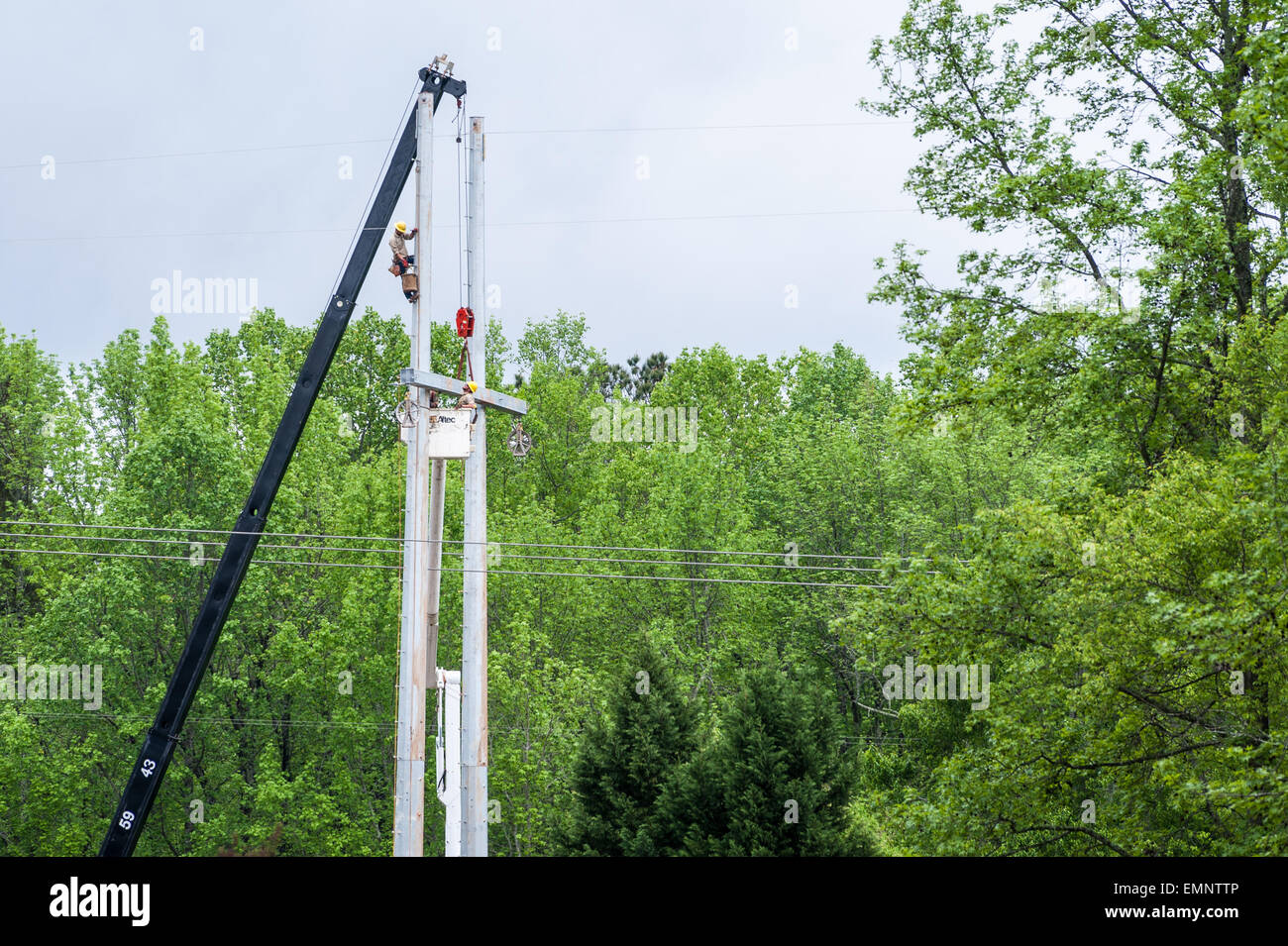 Construction crew installs a high-voltage electric transmission tower behind a residential neighborhood in the Atlanta area. Stock Photo