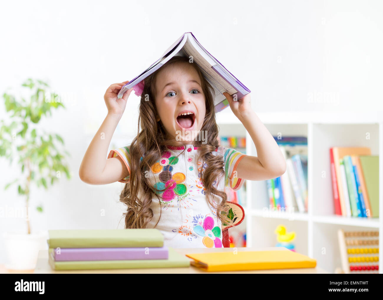 smiling child with a book over her head in primary school Stock Photo