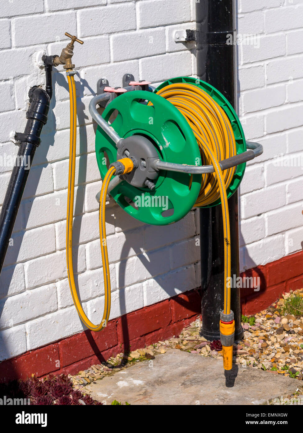 A garden hose reel with yellow kink resisting hose wall mounted for  convenient deployment Stock Photo - Alamy