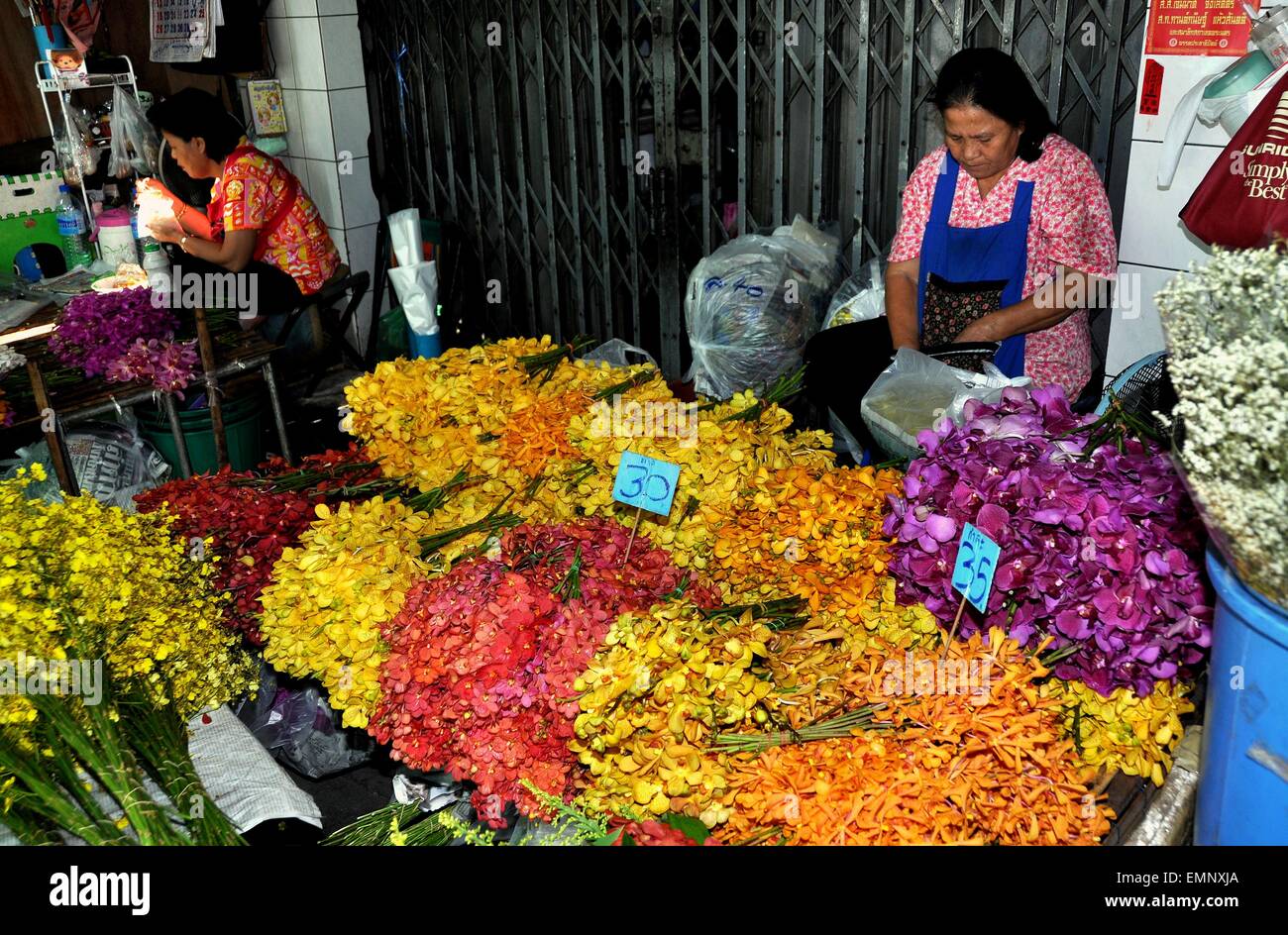 Bangkok, Thailand:  Woman at her stall selling multi-coloured Orchids at the outdoor Bangkok flower market Stock Photo