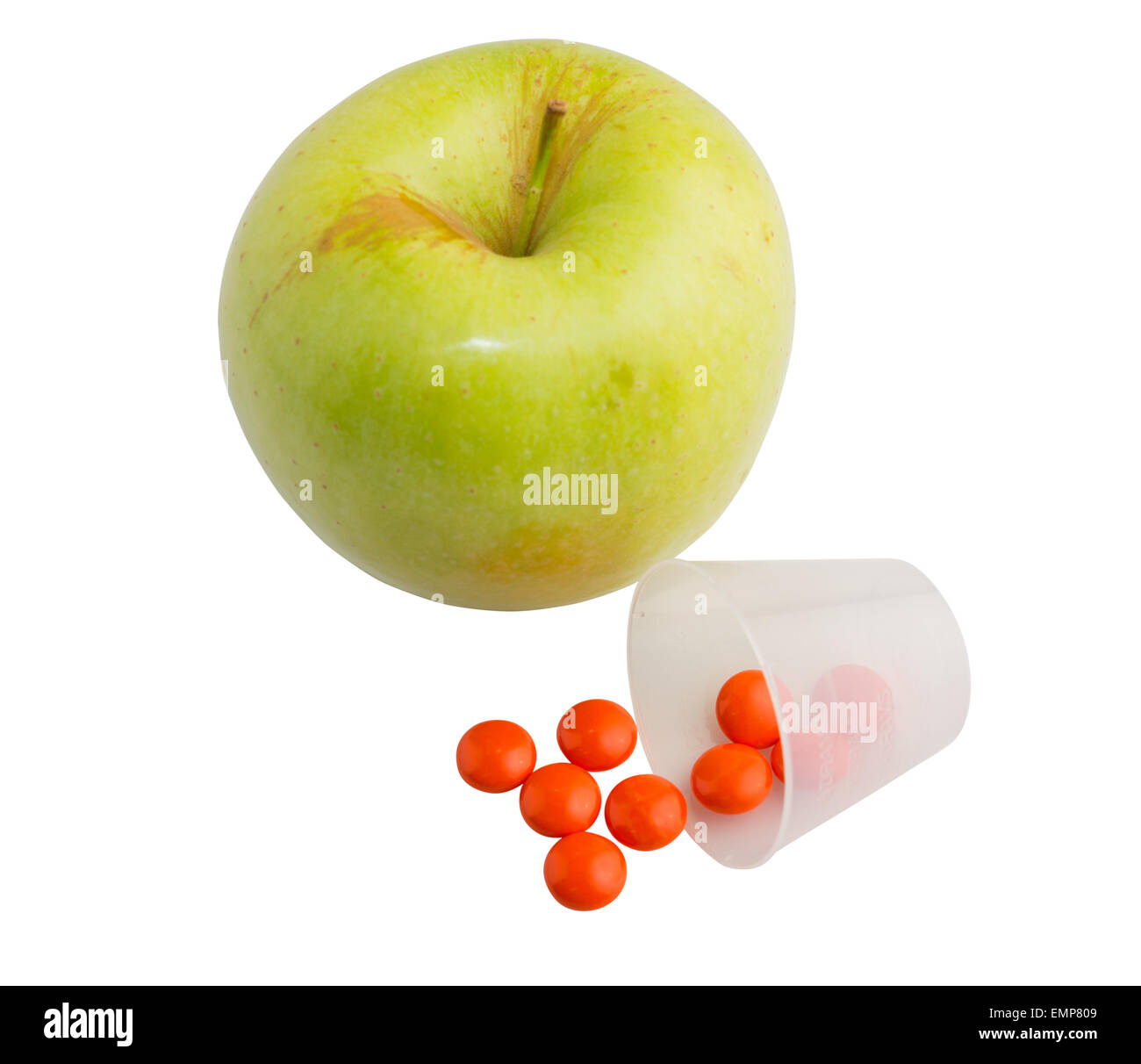 Green fresh apple and red tablets dropped out of a beaker. Stock Photo