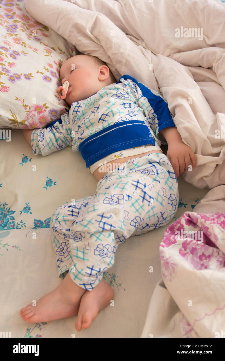 The little boy sleeps on a bed with a pillow and a blanket Stock Photo