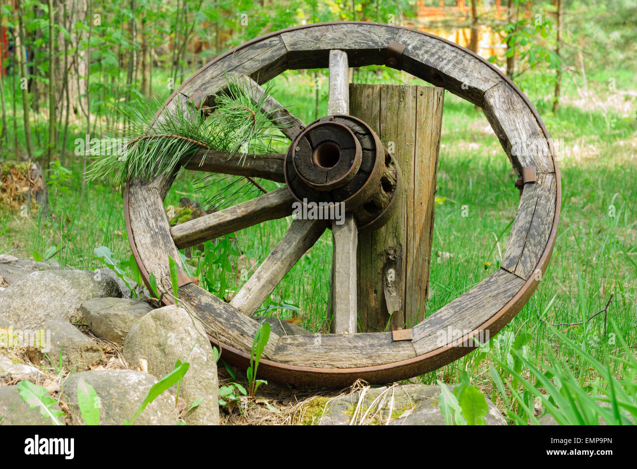 Old wooden wheel from a cart with a metal rim and spokes. Stock Photo