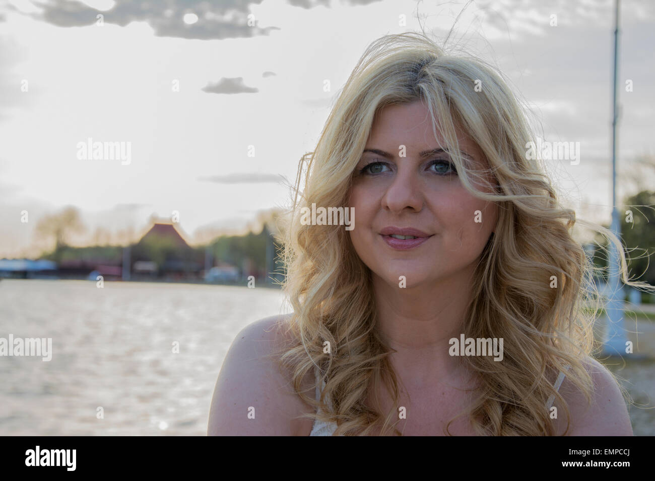 Portrait of beautiful blond curly woman at lake. Stock Photo