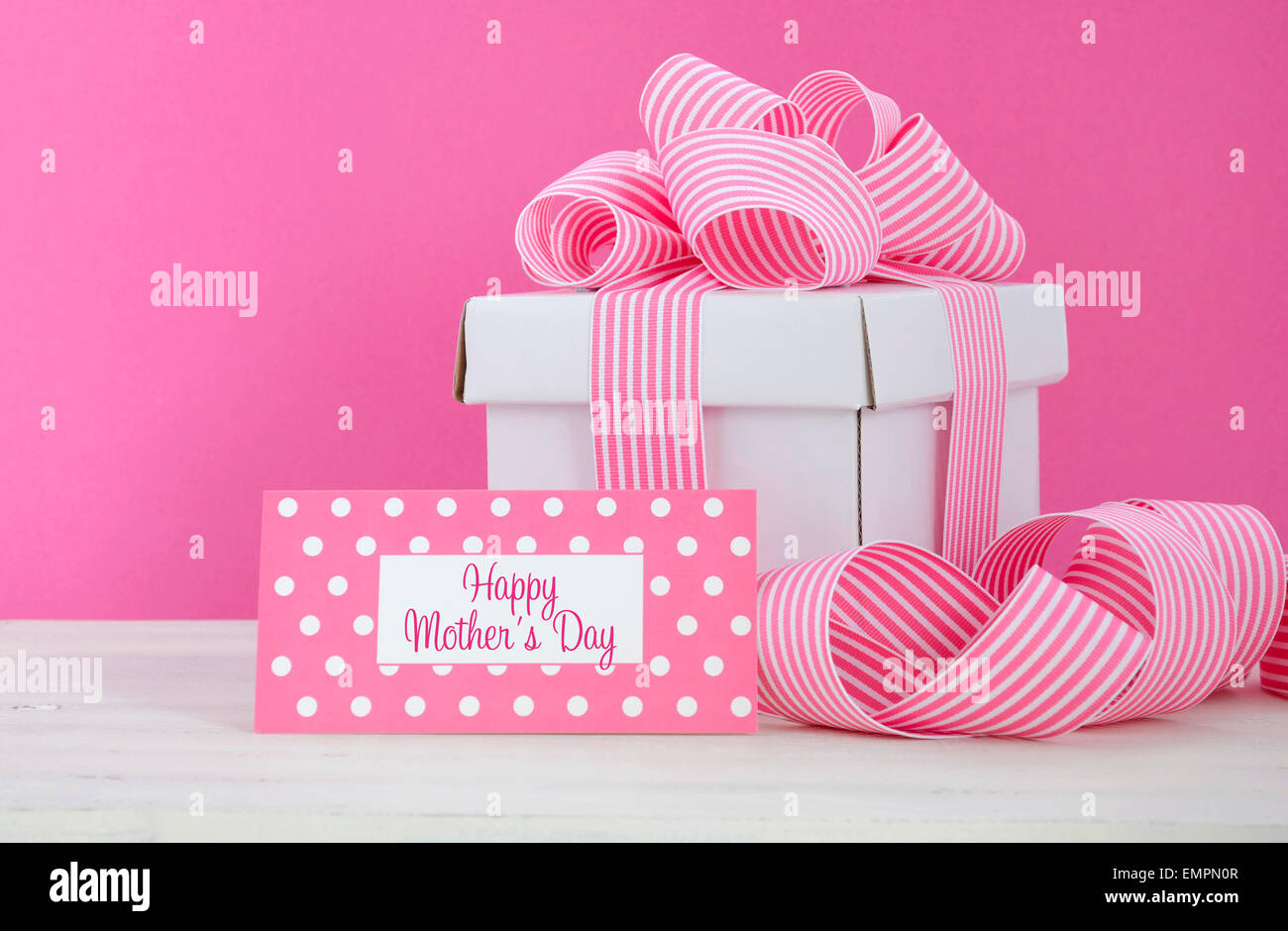 Happy Mothers Day white gift box with pink stripe ribbon with greeting tag  in modern pink and white vintage wood table. Stock Photo