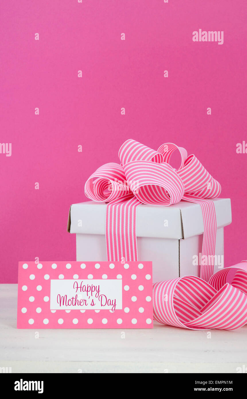 Happy Mothers Day white gift box with pink stripe ribbon with greeting tag  in modern pink and white vintage wood table. Stock Photo