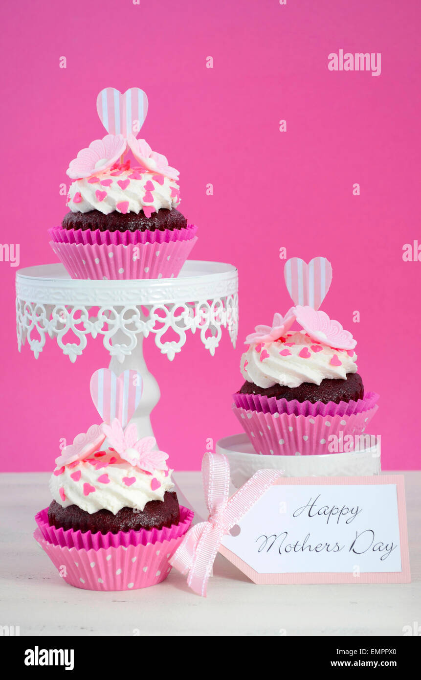 Happy Mothers Day pink and white cupcakes on retro style cake stands on vintage white wood table. Stock Photo