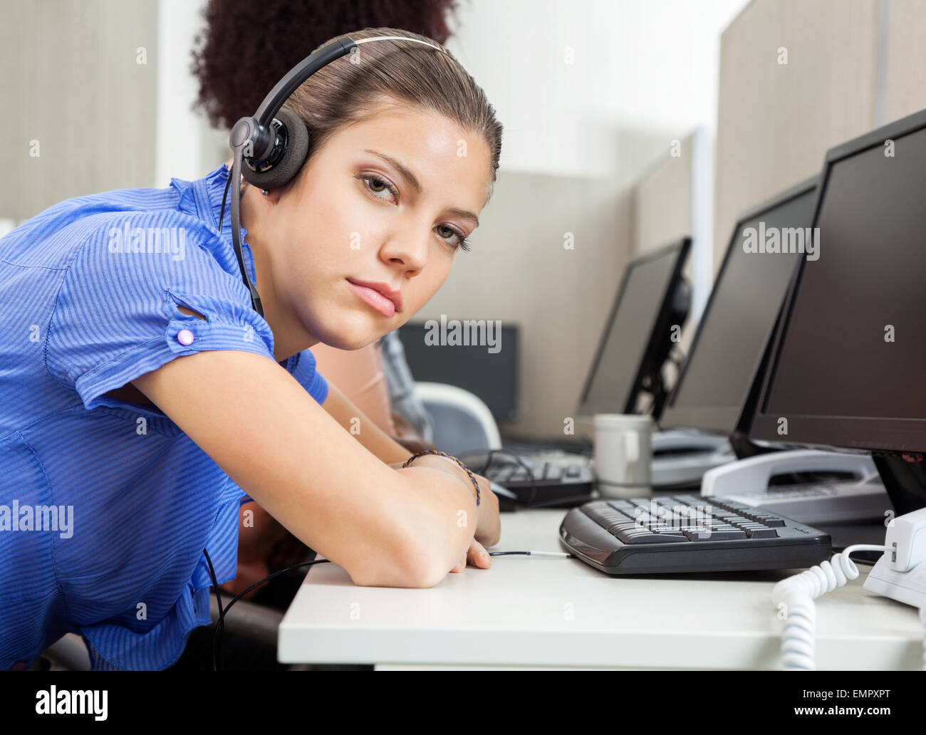 Tired Female Customer Service Representative At Desk Stock Photo