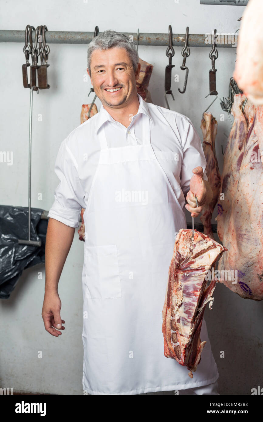 Butcher Holding Meat With Hook In Butchery Stock Photo