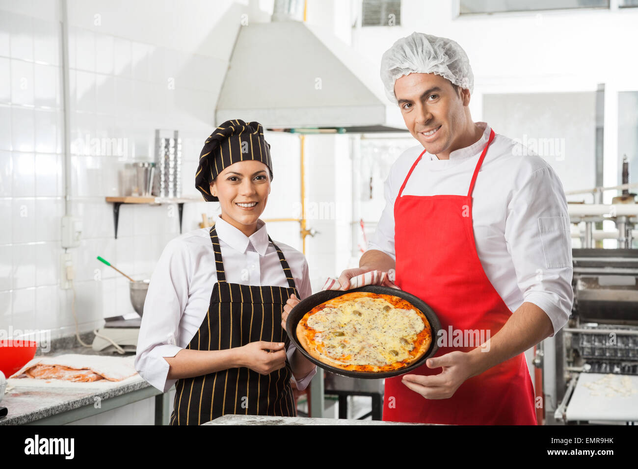 Happy Chefs Presenting Pizza At Commercial Kitchen Stock Photo Alamy