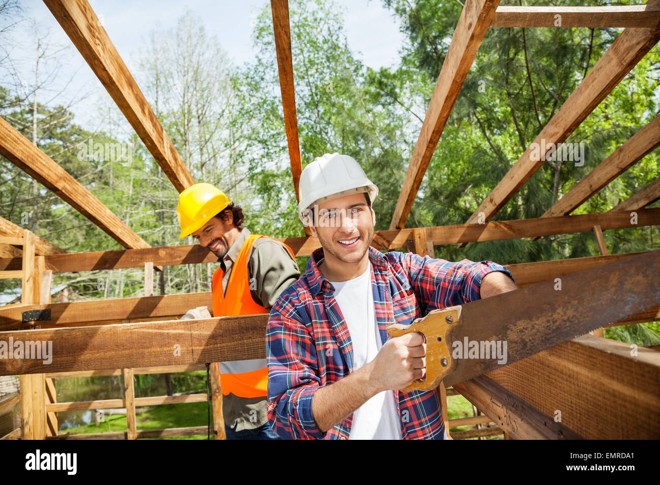 Happy Worker Cutting Wood With Handsaw At Construction Site Stock Photo