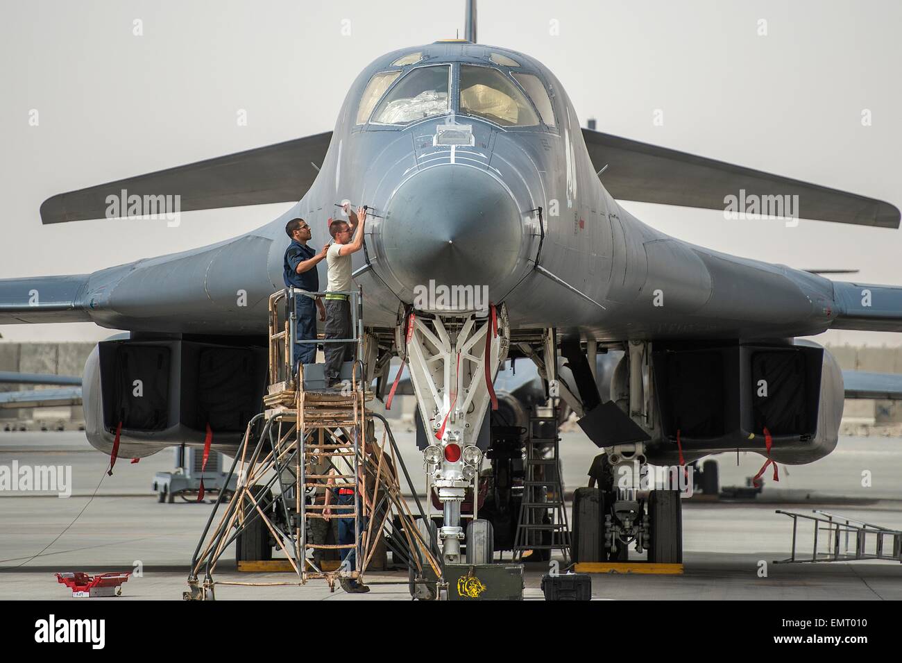 A US Air Force crew chiefs prepare a B-1B Lancer stealth bomber for a mission against Islamic State fighters at Al Udeid Airbase April 8, 2015 in Qatar. Stock Photo
