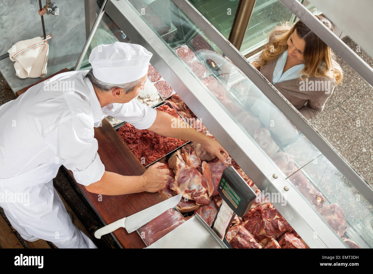 Butcher Selling Meat To Customer At Display Cabinet Stock Photo
