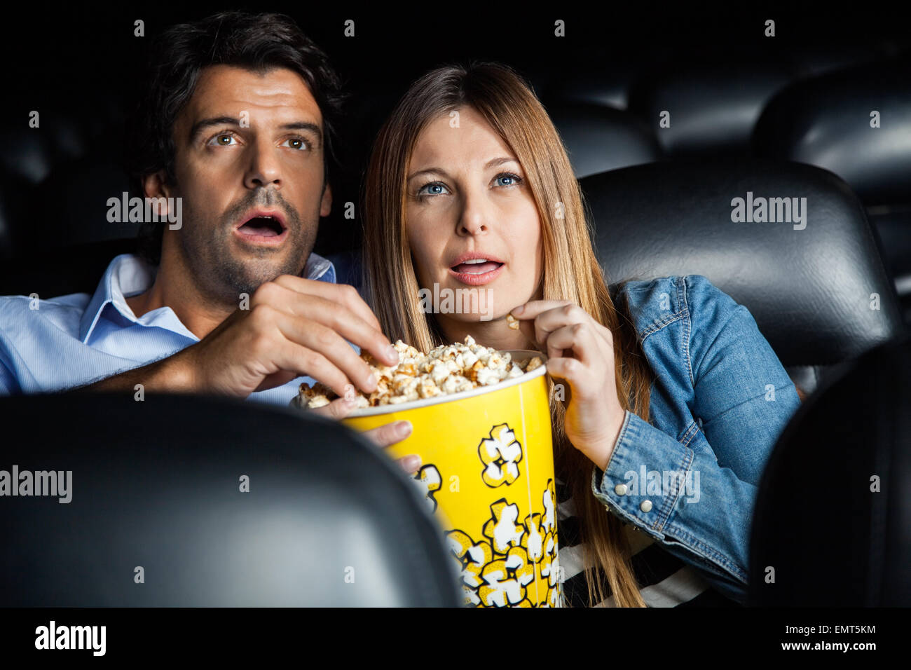 Shocked Couple Watching Movie In Theater Stock Photo