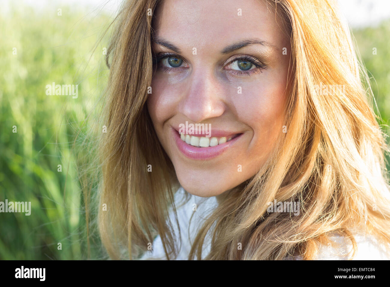 young blond woman girl face portrait outdoors green grass field sunny sunlight summer Stock Photo