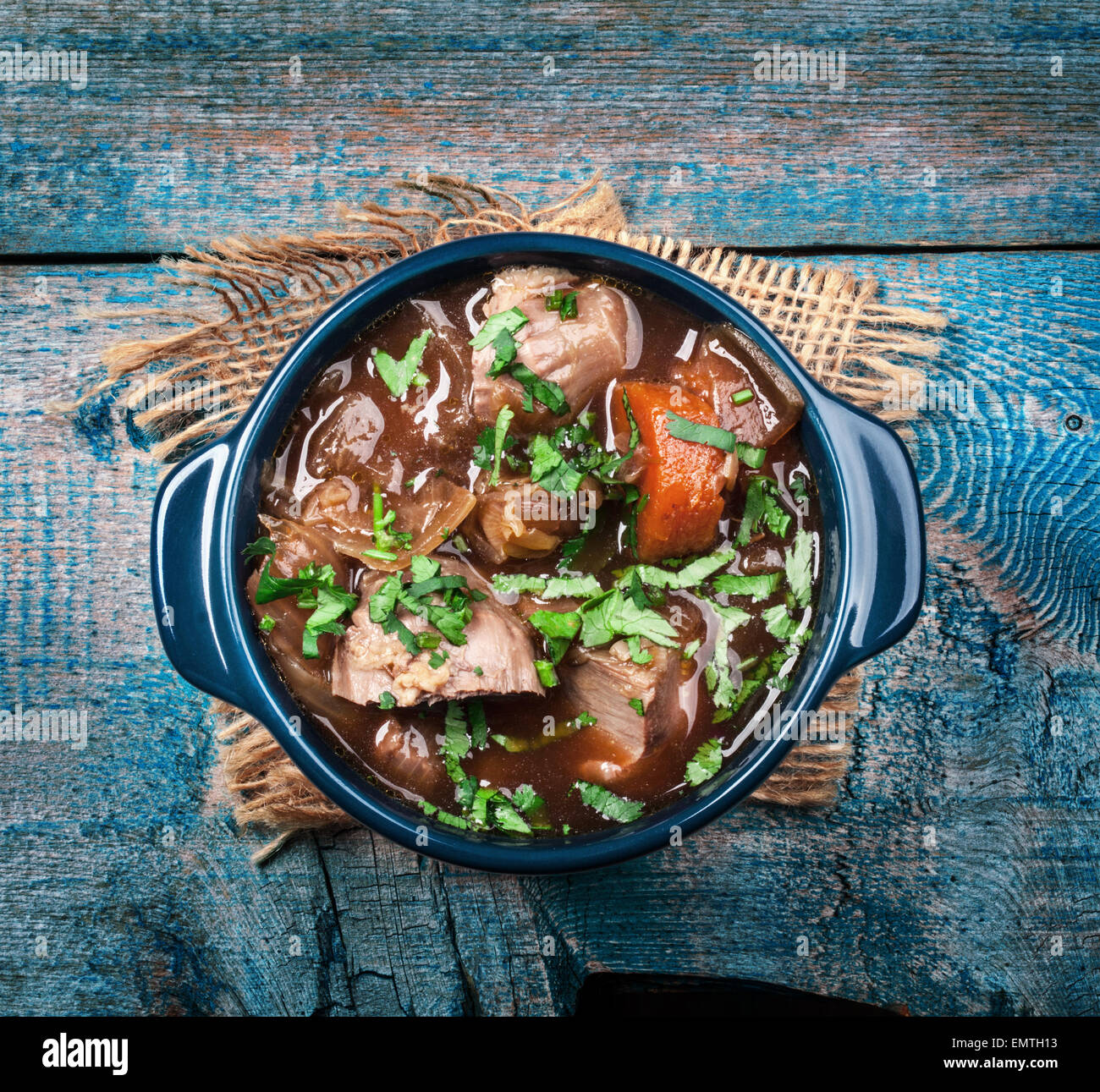 Meat stew with vegetables and herbs on old wooden table Stock Photo