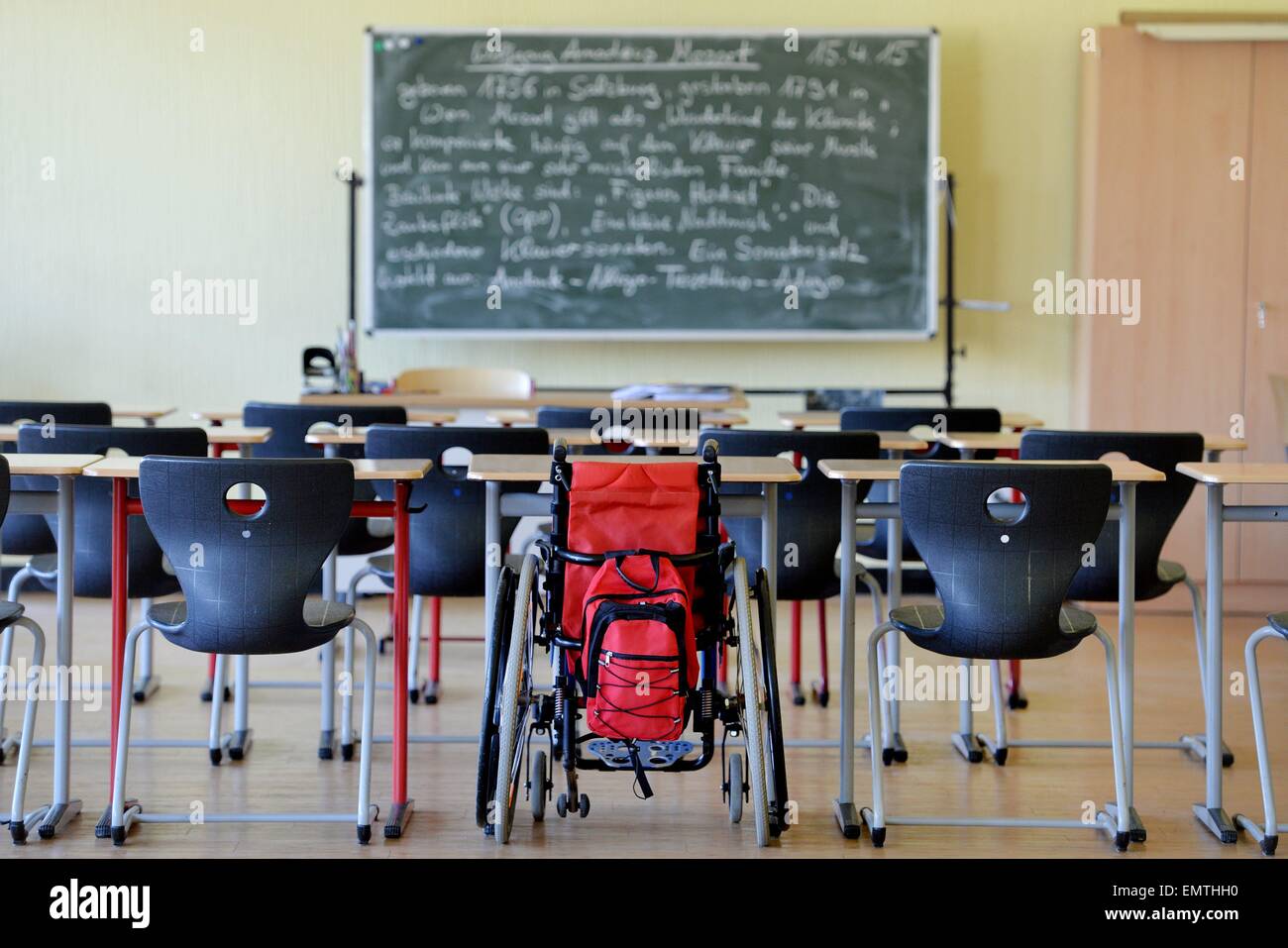 A wheelchair standing between other chairs in a school classroom./picture alliance Stock Photo