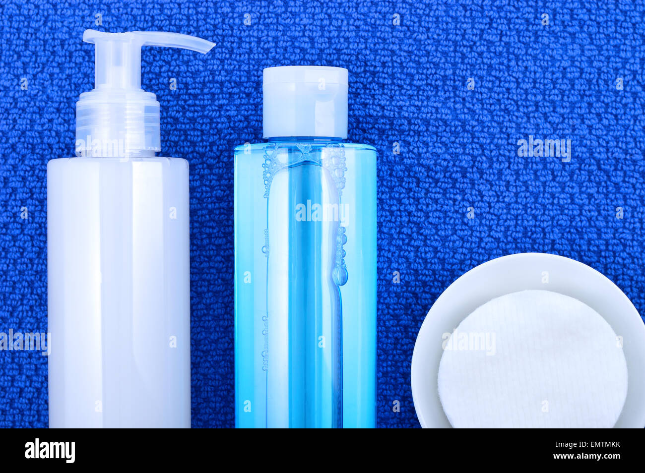 Daily cleansing cosmetics - face wash cleansing gel, smoothing toner and cotton cleansing pads on navy blue towel. Stock Photo