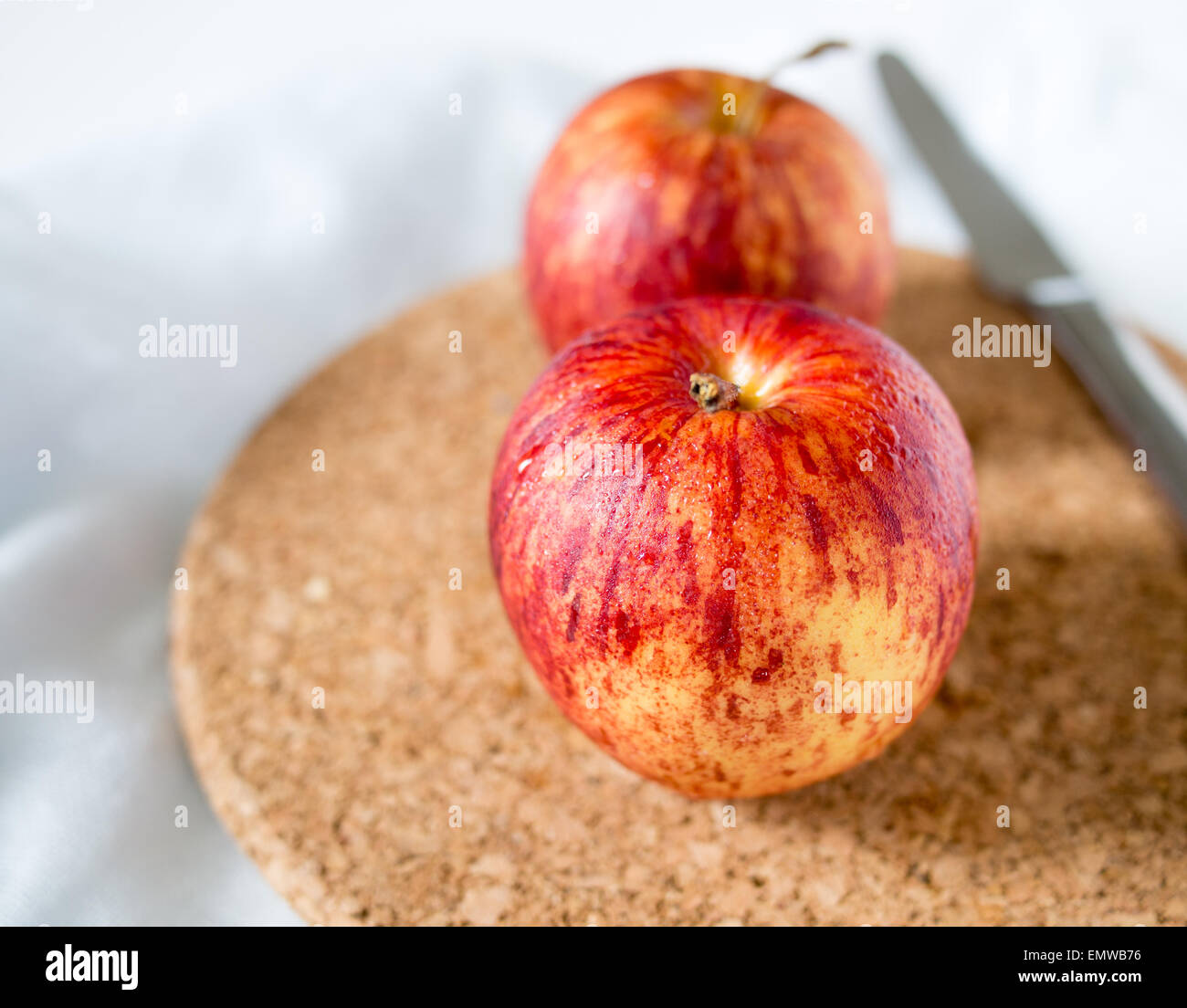 Two red apples on cork mat Stock Photo