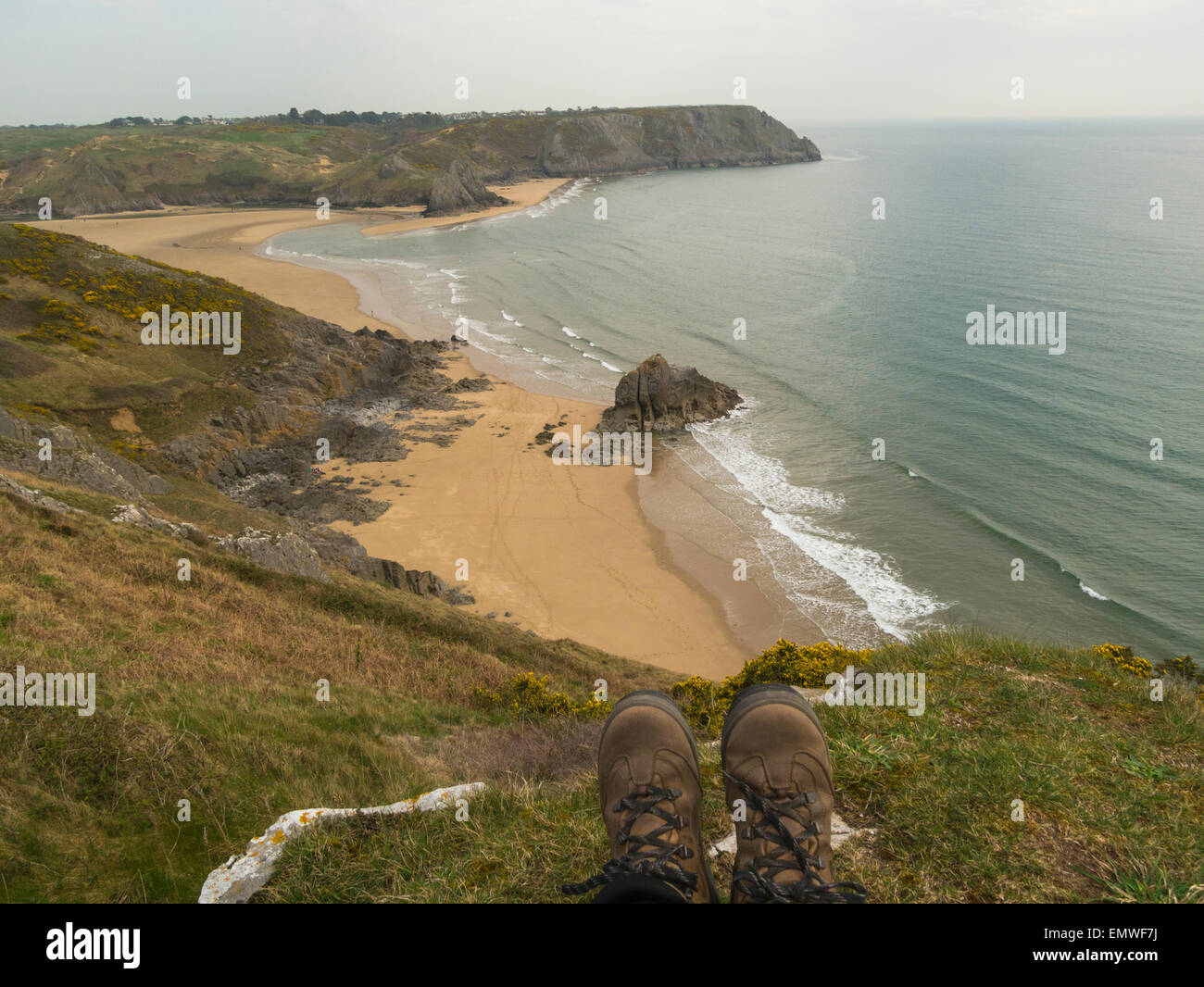 Pair walking boots over view down to Threecliff Bay Gower Peninsula