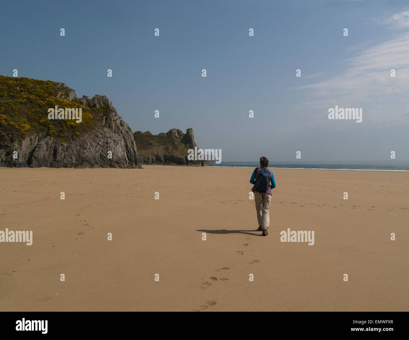 Female walking across pristine sands Oxwich Bay Gower Peninsula South