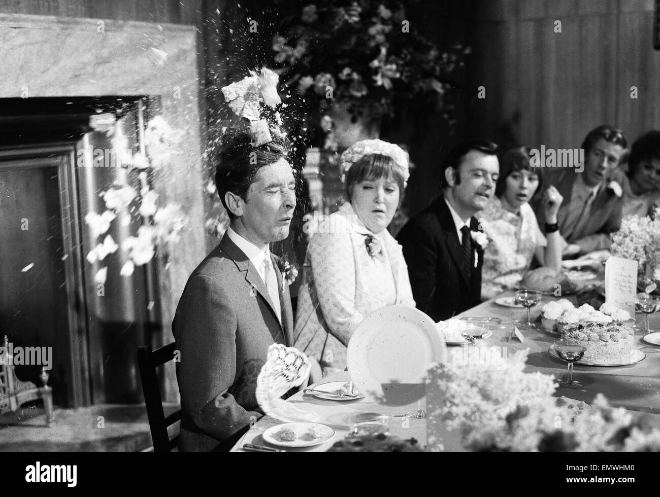 Filming 'Carry on Loving' at Pinewood Studios. Kenneth Williams sitting through five takes of having a cream cake thrown in his face with Patsy Rowlands sitting next to him looking on. 6th May 1970. Stock Photo