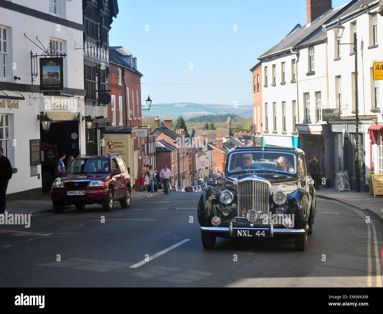 A vintage car drives up a curved road in the centre of the historic