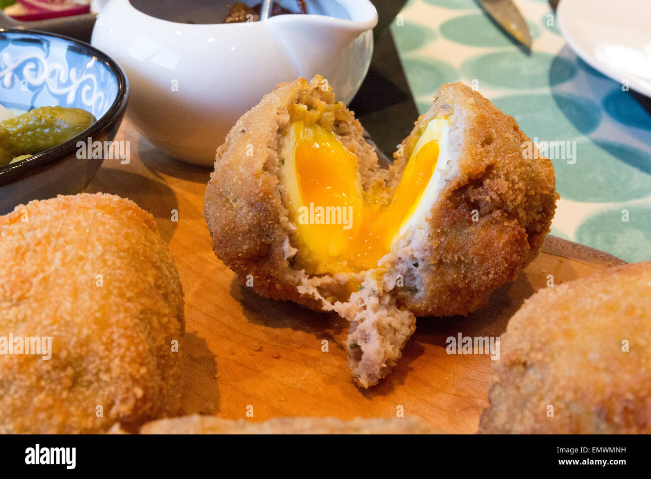 A slightly runny scotch egg cut open to show the egg gently pouring out