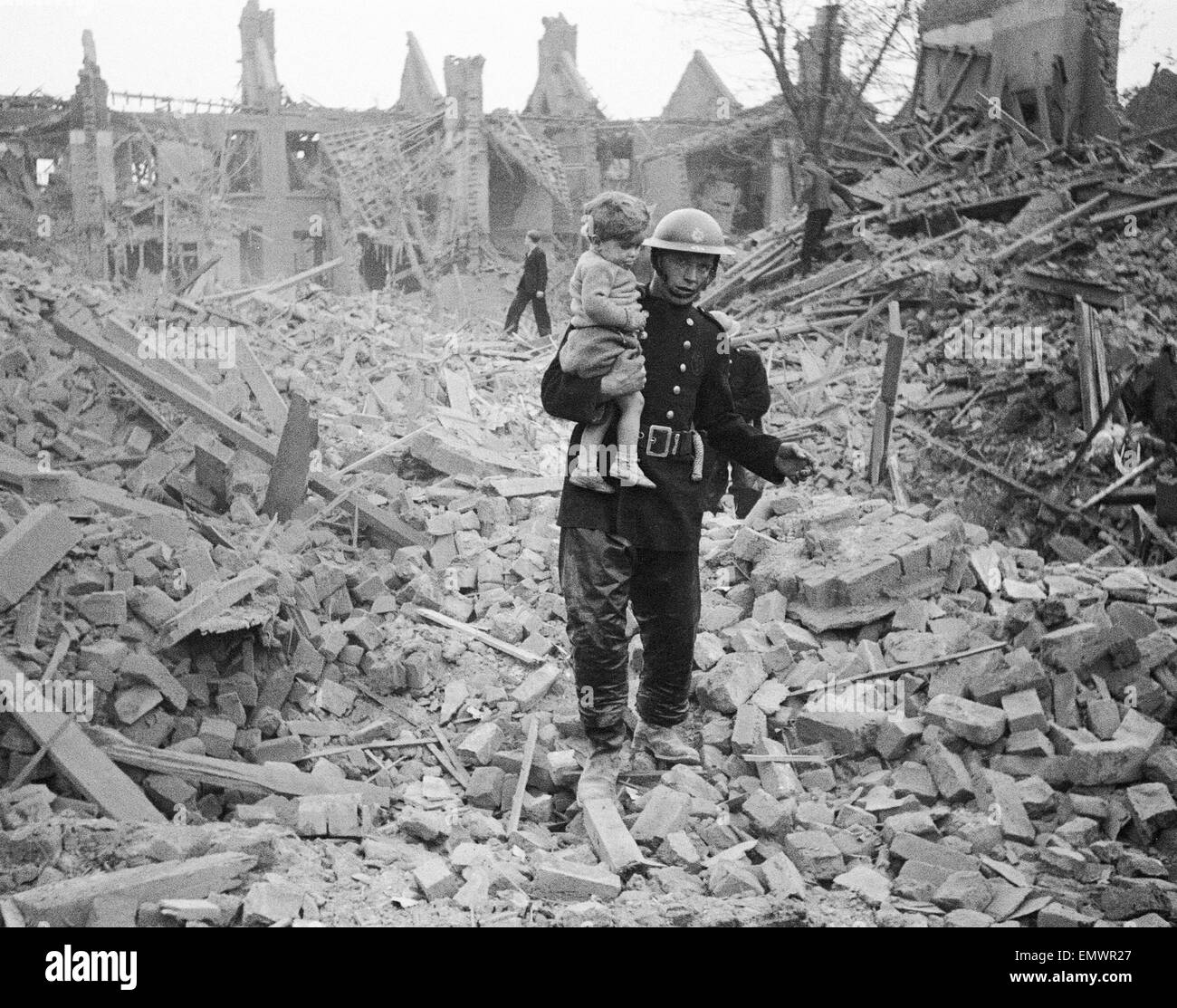 A fireman carries a young boy out of the rubble after a bombing raid. Stock Photo