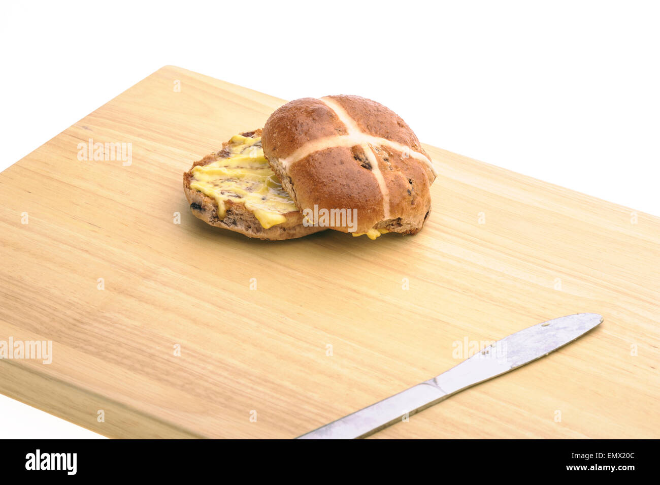 Hot cross bun with knife on a wooden board. Stock Photo